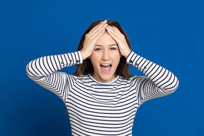 Portrait of young woman against blue background