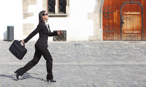 Full length of woman holding umbrella in city