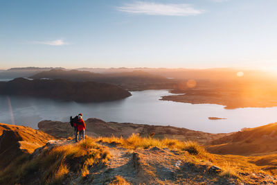 Man looking at mountains against sky during sunset