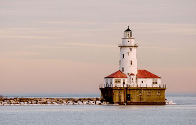 Lighthouse by sea against building