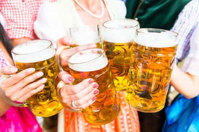 Midsection of friends holding beer glasses