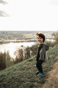 Side view of boy standing on field against sky