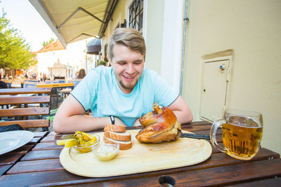 Portrait of smiling young man having food at cafe