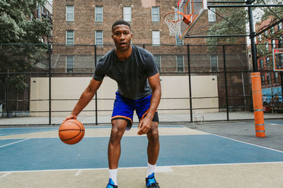 Young man practicing basketball in court