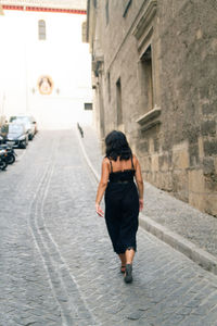 Rear view of woman walking on footpath in city