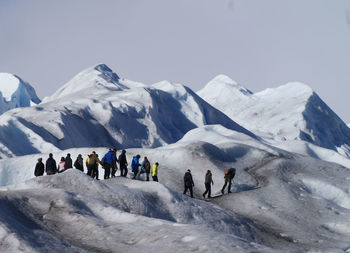 People on snowcapped mountain against sky