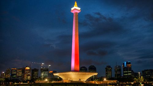 The illuminated buildings in the city of monas against the sky at night