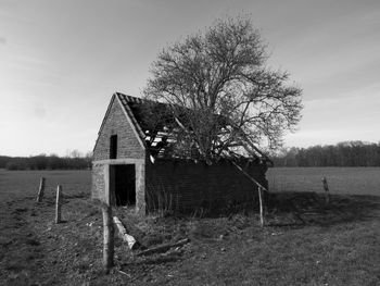 Built structure by trees on landscape against sky