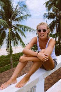 Portrait of a smiling young woman sitting on railing