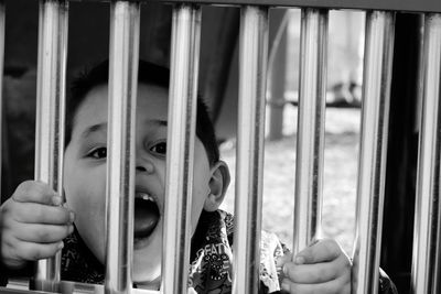 Close-up portrait of boy screaming through window