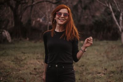 Portrait of smiling young woman wearing sunglasses standing outdoors