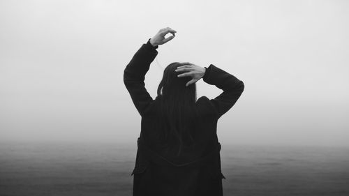 Silhouette man with arms raised against sky during sunset