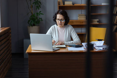 Businesswoman using laptop while sitting on table