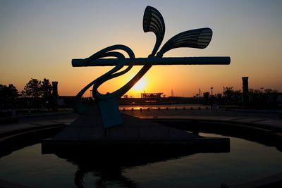 Silhouette sculpture against sky during sunset