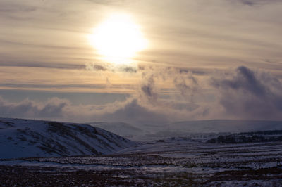 Scenic view of snow covered landscape against sky during sunset