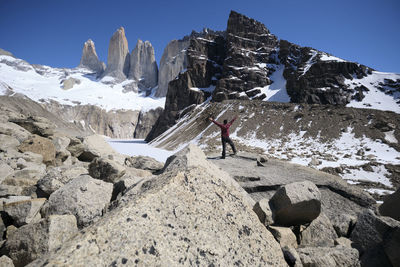 Rear view of man with arms outstretched standing against mountains