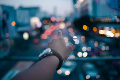 Cropped hand pointing against illuminated city