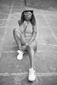 Full length portrait of young woman sitting outdoors