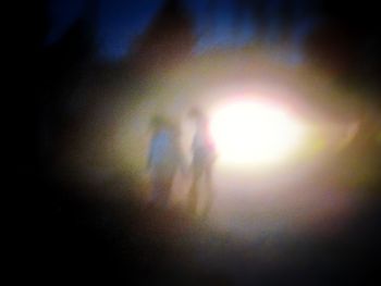 Defocused image of silhouette people standing against illuminated sky