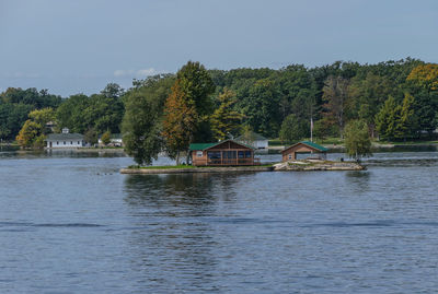 Scenic view of lake by trees and building against sky