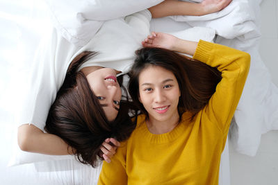 High angle portrait of two women lying on bed at home