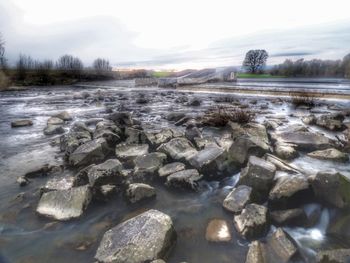 Surface level of rocks in water against sky