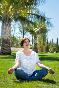 Full length of woman meditating while sitting at park