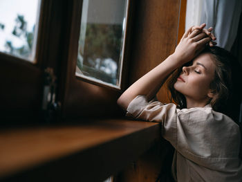 Side view of woman looking through window