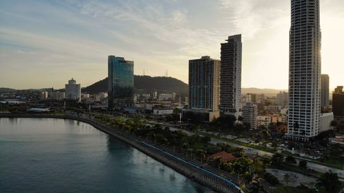 River amidst buildings against sky during sunset