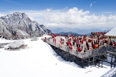 People over bridge on mountain against sky during winter