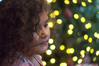Close-up of girl looking away against illuminated lighting