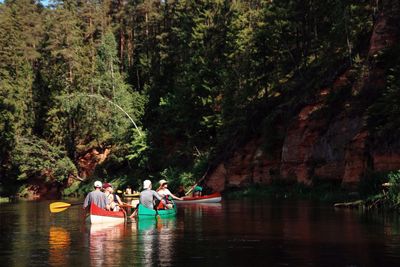 People boating on river against trees