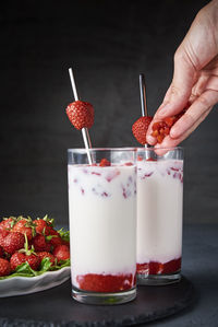 Midsection of person holding ice cream in glass on table