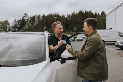 Car salesman giving customer keys to car