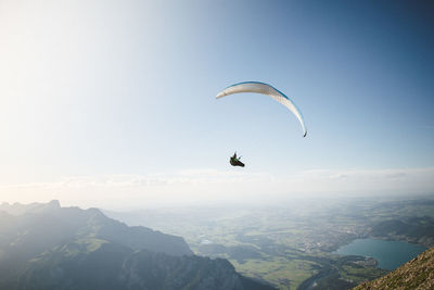 Man paragliding over mountains against sky