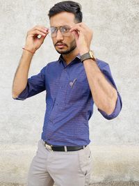 Young man looking away while standing against wall
