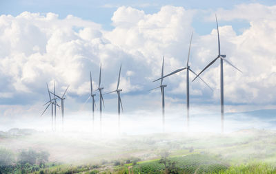 Windmills on field against sky