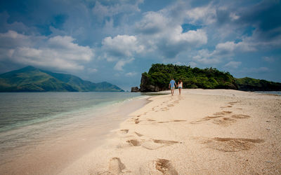 Rear view of man standing on beach against sky