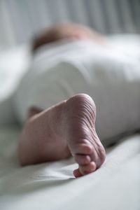 Low section of baby boy relaxing on bed