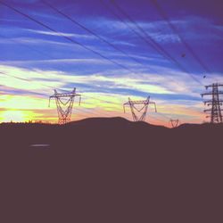 Low angle view of silhouette electricity pylon against sky