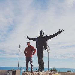 Full length of man standing by statue against sky