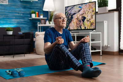 Full length of senior man meditating at home