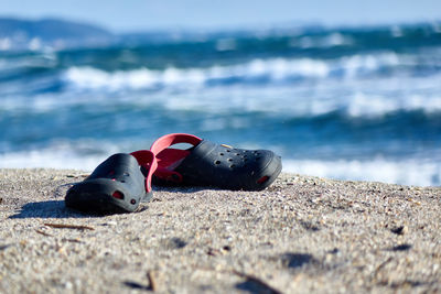 Close-up of shoes on beach against sky