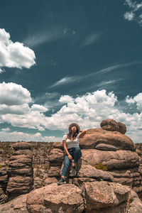 Full length of man sitting on rock against sky