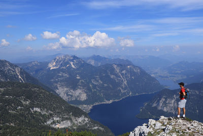 Rear view of man standing on mountain against sky
