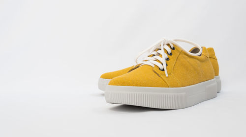 Close-up of yellow shoes over white background