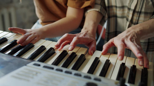 Midsection of teacher and student playing piano