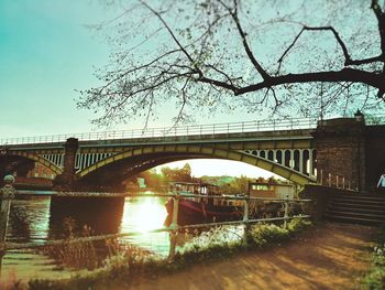 Bridge over river in city against sky