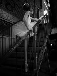 Low angle view of female ballet dancer stretching on steps in abandoned building