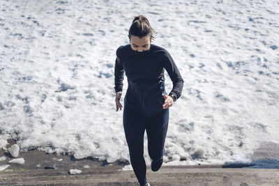 Attractive young brunette woman running through the city after a big snow storm